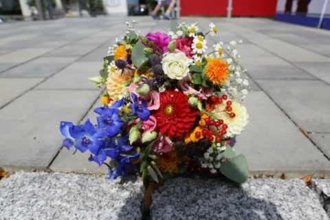 Bunter Blumenstrauß mit verschiedenen Blumen und Beeren auf einem Gehweg aus Pflastersteinen.