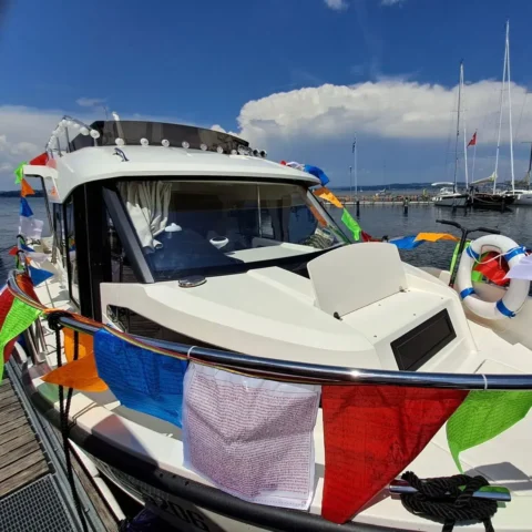 Weiße Yacht mit bunten Wimpeln an einem sonnigen Tag im Hafen.