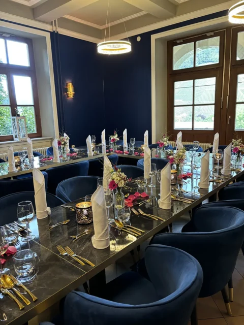 Elegante Hochzeitstafel mit festlicher Dekoration und stilvollen blauen Stühlen in einem stilvollen Raum.