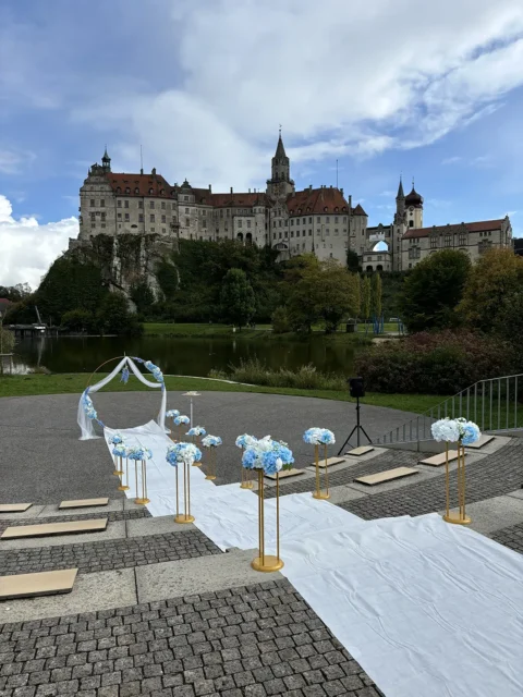 Hochzeitszeremonie vor Schlosskulisse mit blauen und weißen Blumen dekoriert – perfekte Kulisse für Herzensreden.